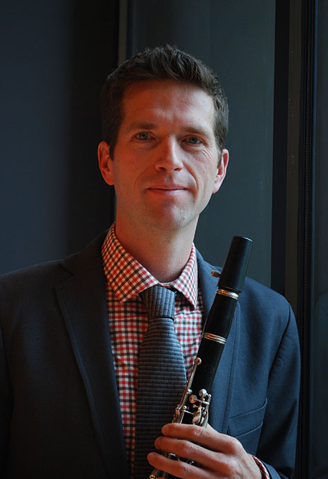 Photo of Blake McGee in a gingham shirt holding a clarinet
