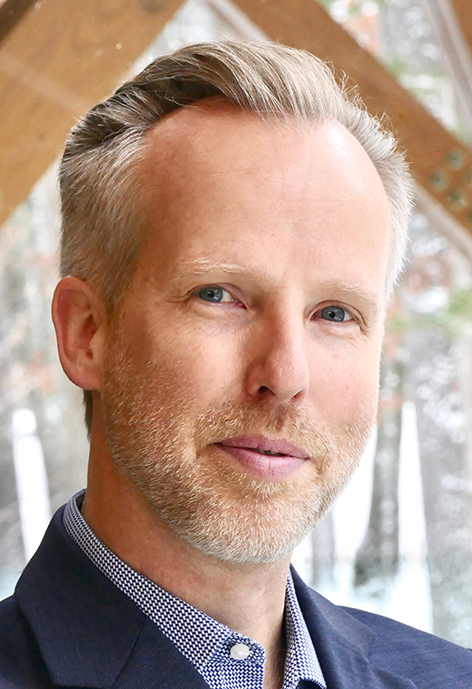 Photo of Director of Bands Dr. Matt Schlomer outdoors in a blue suit