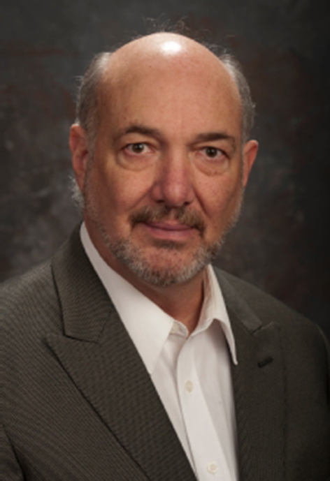Photo of Greg Strampe in a gray suit with a gray background