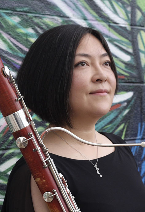 Photo of Kaori Uno-Jack holding a bassoon in front of a mural