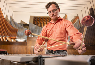 Graduate student playing on a percussion instrument