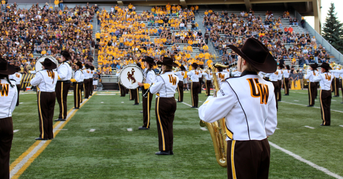 student playing in band on football field