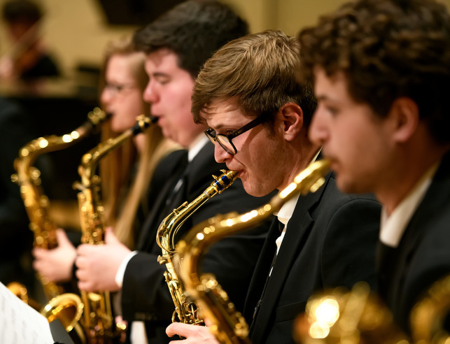 Group of four jazz saxophonists preforming at a concert