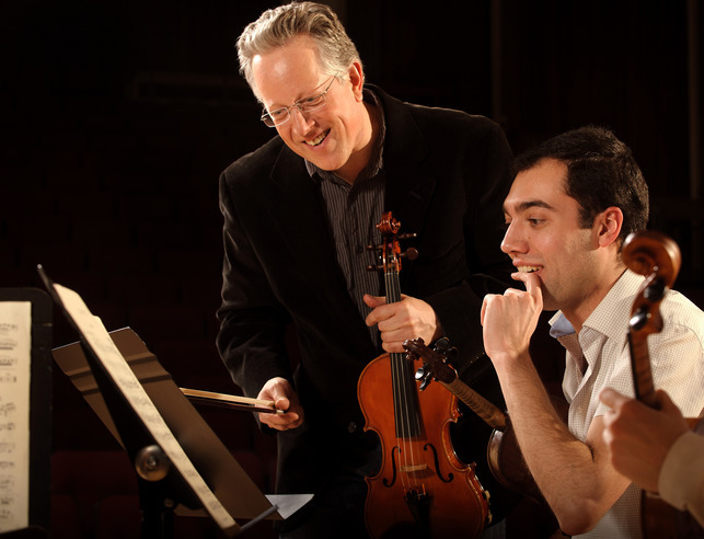 String faculty member coaching violin student on music.
