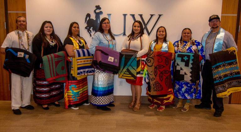 a group of graduates with native design blankets