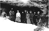 Historic photo of people standing by cave