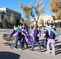 group of costumed people with purple balloons on them pushing shopping cart