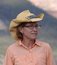 woman in cowboy hat standing with mountains in background