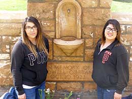 two young women kneeling beside sandstone monument