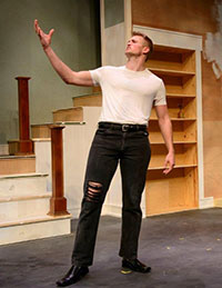 man standing on set for play, with arm extended in front of him