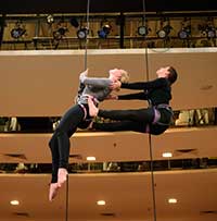 young man and woman on lhanging from harnesses for vertical dance