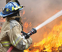 firefighter aiming fire hose at a huge blaze