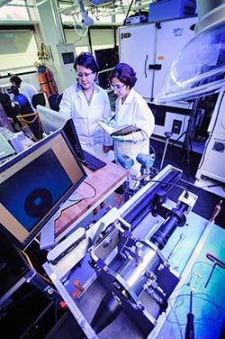 two women in lab coats working in a lab full of high tech equipment