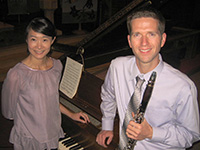 woman and man standing in front of piano with man holding clarinet
