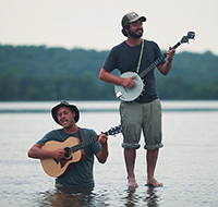man with guitar in lake and man with banjo beside him playing instruments