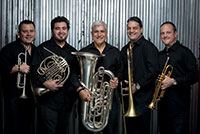 five men standing in a row holding brass instruments
