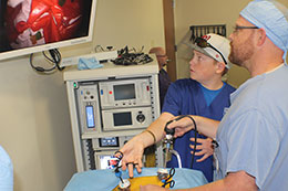 man in scrubs and young man looking at screen while using equipment