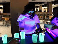 woman pouring liquid into cups glowing under black light