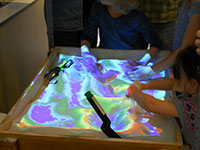 children playing in sand table with colored projection overlay