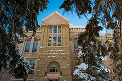 sandstone brick building with snow on it framed by snowy evergreen trees