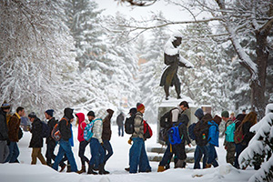 people walking in snow beside statue