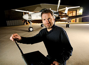 man with a laptop computer in front of an airplane