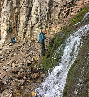 woman standing by rock wall and waterfall