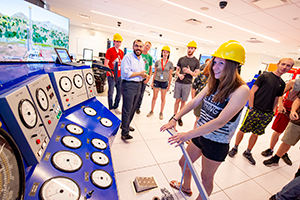 students in hard hats at equipment simulator panel