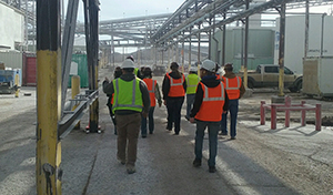 Group of people in hardhats and safety vests walking in industrial area