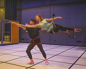 man and woman wearing flying harnesses on a stage