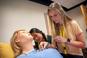 a high school student examines a training mannequin