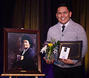 man standing beside a portrait of a woman man standing beside a portrait of a woman