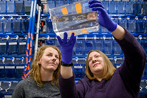 two women look at a container with fish swimming in it