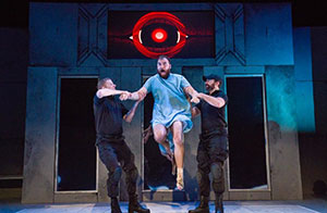 Two men holding on to an escaping man on a stage