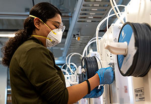 woman feeding filament into 3D printer