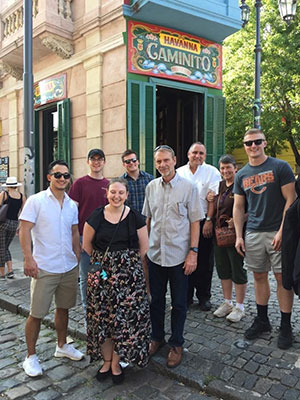 group of people standing outside on a cobblestone street and sidewalk