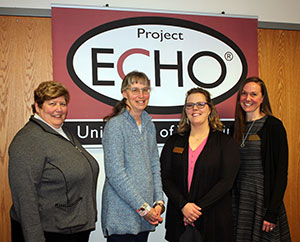 four women posing in front of a sign that says ECHO