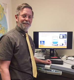 man standing by a computer screen