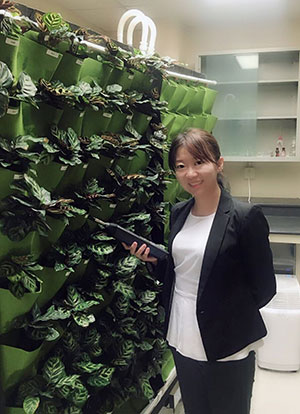 woman standing by a wall of plants