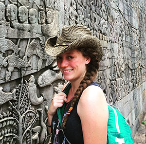 woman standing in front of wall of ancient stone carvings