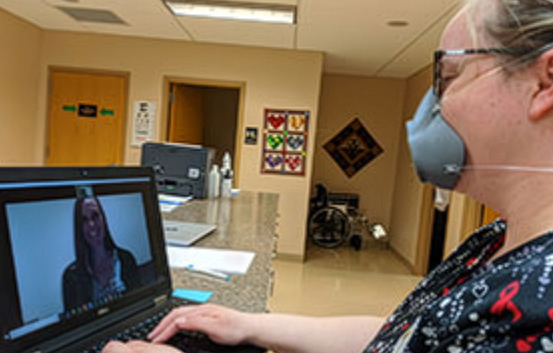 woman in medical setting talking to someone via laptop computer