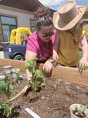 woman and small child working in a raised garden bed