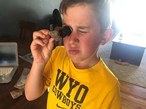 boy examining a rock through a lens