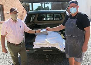 two men standing by  sacks of grain in the back of a truck