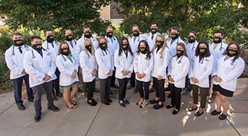 group of people posing outside wearing white medical coats