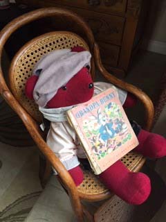 a teddy bear with a book in a rocking chair