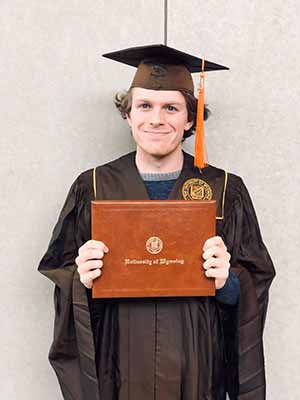 man in cap and gown holding diploma