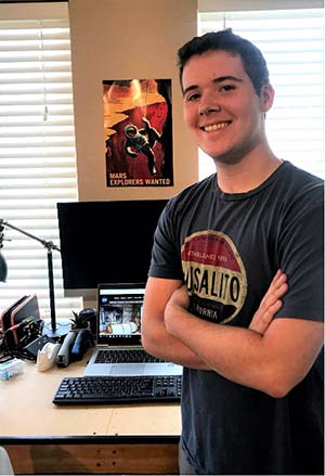 man standing beside desk with computer