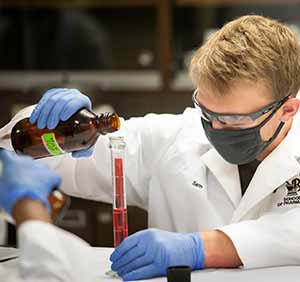 man pouring fluid into a glass tube