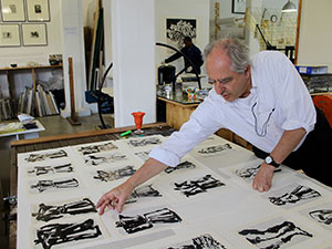 man leaning over table with prints on it